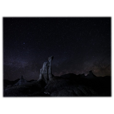 Formações rochosas escuras ao luar sob um céu cheio de estrelas