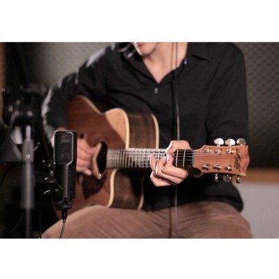 Homem tocando guitarra acústica de madeira com microfone em estúdio