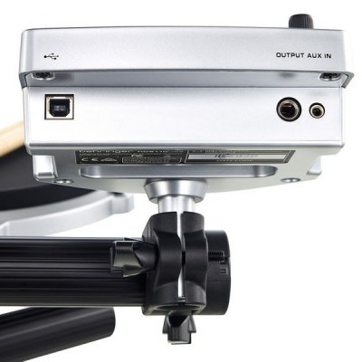 Detalhe da parte traseira e inferior de equipamento eletrónico cinzento com conexões USB e AUX em suporte preto