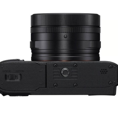 Base de câmera fotográfica digital preta com lente acoplada e botão de trava.