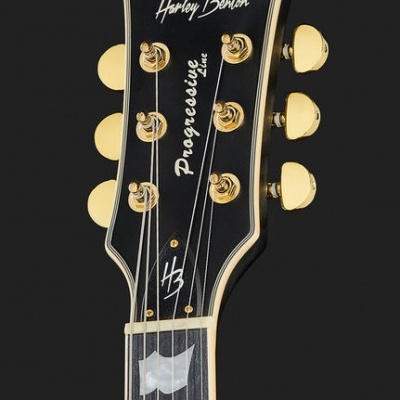 Cabeça de guitarra elétrica preta com tarraxas douradas e gravações brancas