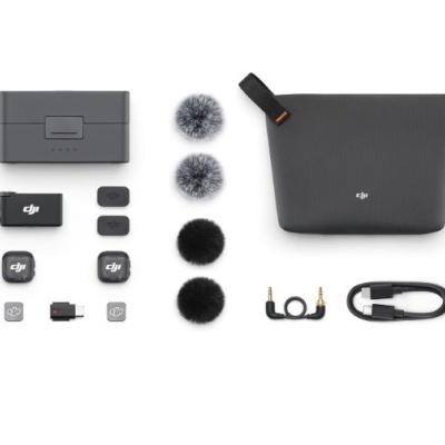 Acessórios DJI organizados numa superfície branca com estojo cinza escuro, microfones e vários adaptadores e cabos.