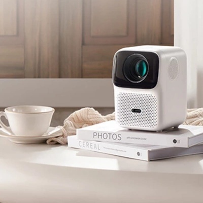 Projetor branco sobre livros numa mesa branca com chávena e pires ao lado