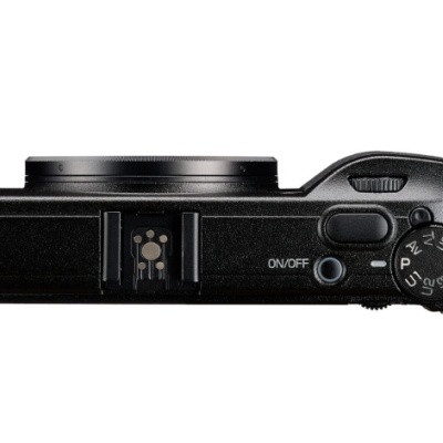 Vista superior de uma câmera digital compacta preta com botão ON/OFF e seletor de modo.
