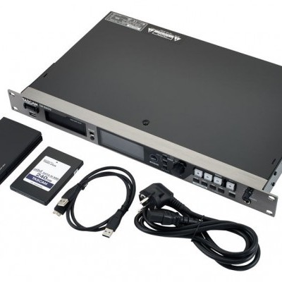 Equipamento eletrónico preto com acessórios e cabos sobre fundo branco