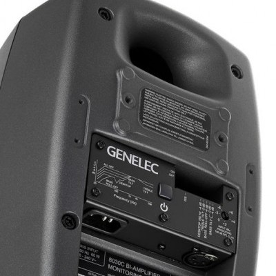 Coluna de monitorização Genelec preta com controlos e etiquetas técnicas no painel traseiro