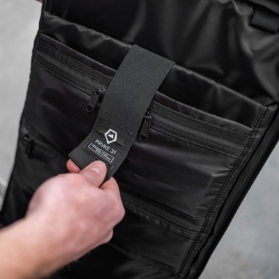 Bolsa preta com fecho e etiqueta Private 311, mão segurando aba de velcro