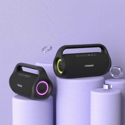 Dois altifalantes portáteis Tronsmart pretos com iluminação colorida, sobre pilares roxos