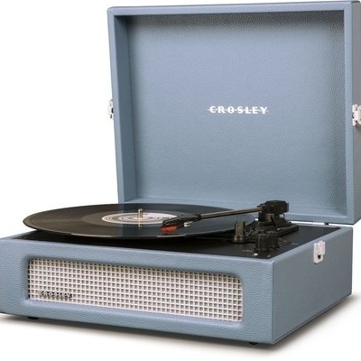 Gira-discos Crosley portátil azul claro com disco de vinil preto.