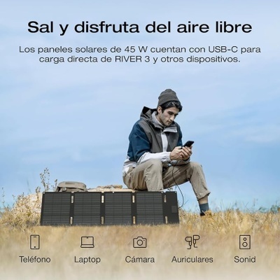 Painéis solares portáteis pretos e homem sentado num campo seco usando smartphone.