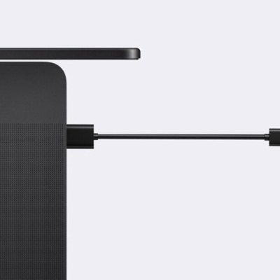 Portátil preto ligado a um dispositivo pequeno preto com botão laranja e logo branco