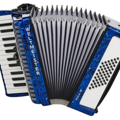Acordeão azul com teclado de piano e botões, texto WELTMEISTER e PERLA III S visível