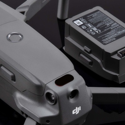 Drone DJI cinzento com bateria ao lado sobre fundo preto