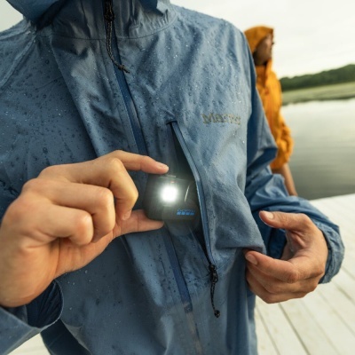 Casaco impermeável azul com bolso vertical no peito e dispositivo luminoso no bolso