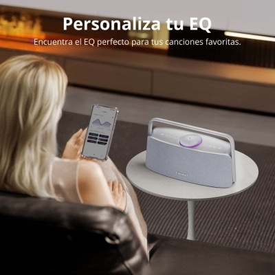 Pessoa a usar smartphone junto a coluna branca e cinza sobre mesa redonda