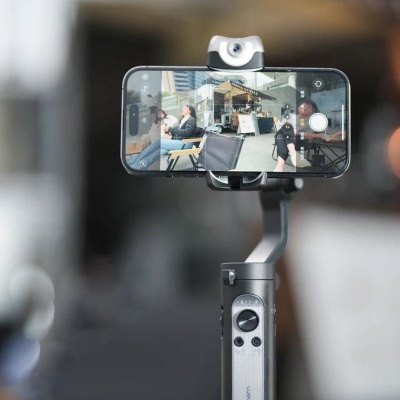 Smartphone preso a estabilizador cinza com lente adicional