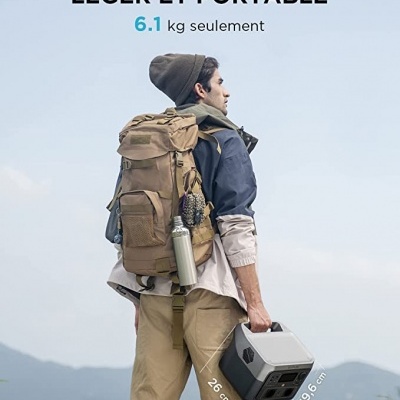 Homem com mochila castanha e roupa casual segurando um dispositivo portátil cinza em ambiente de montanha ao ar livre