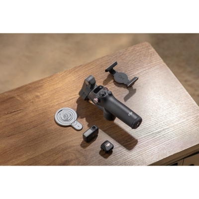 Estabilizador de câmara DJI OM 5 e acessórios numa mesa de madeira