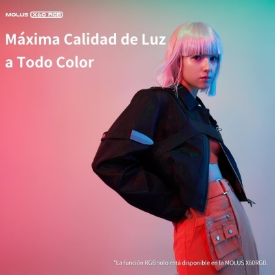 Jovem com cabelo loiro e rosa vestindo casaco preto e calças laranja sob luzes rosa e azul