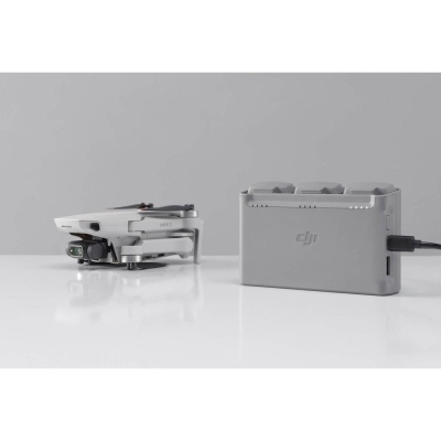 Drone DJI cinza compacto com carregador cinza ao lado