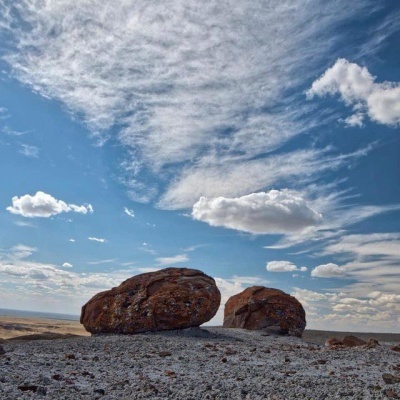 Rocha castanha em solo rochoso com céu azul e nuvens