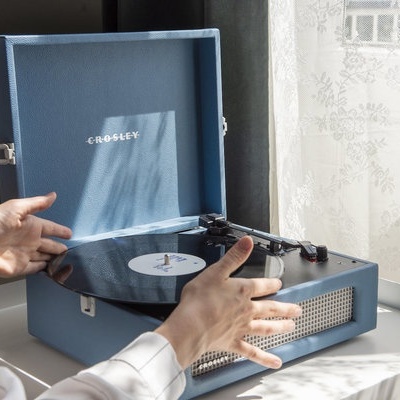 Gira-discos azul tipo mala com disco de vinil preto e texto CROSSFLEY