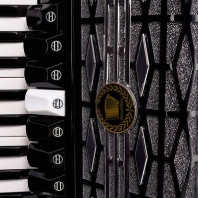 Detalhe de acordeão preto com teclas, botões e padrão prateado