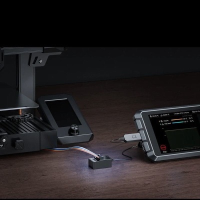 Dispositivo de teste eletrônico com ecrã digital conectado a máquina preta sobre mesa de madeira