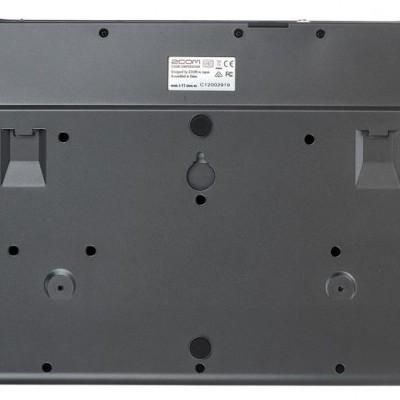 Parte traseira de teclado preto com etiqueta branca e pés ajustáveis