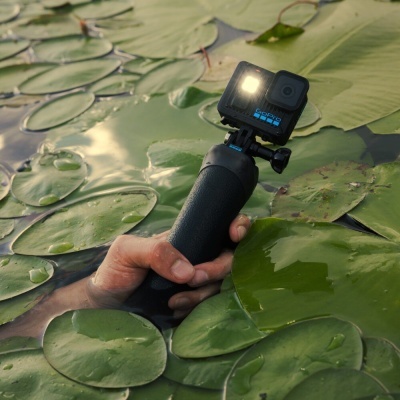 Câmara de ação preta com suporte de mão na água entre folhas de nenúfar