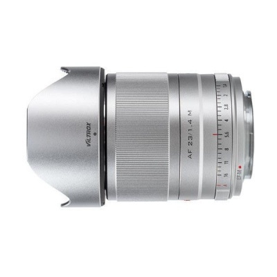 Objetiva de câmera fotográfica prateada com anéis de ajuste e proteção frontal.