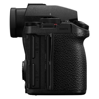 Lado de câmara fotográfica preta com punho texturizado e ranhuras para cartões.