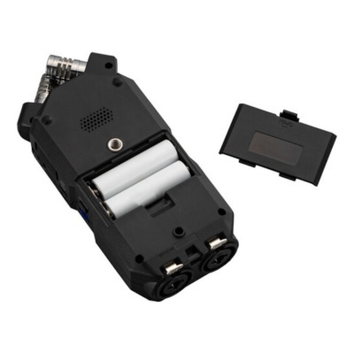 Dispositivo eletrónico preto aberto com pilhas AA visíveis e tampa destacada ao lado.