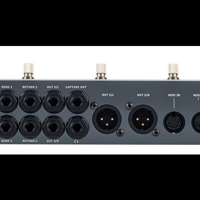 Interface de áudio preta com múltiplas entradas e saídas em superfície branca