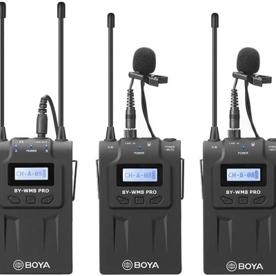 Três transmissores de microfone sem fios pretos com antenas e ecrãs digitais azuis, microfones de lapela com espuma preta.