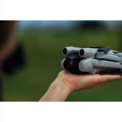 Drone dobrado cinza com detalhes pretos e laranja numa mão