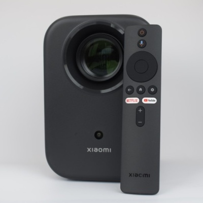 Projetor Xiaomi preto com controlo remoto e botões Netflix e YouTube em fundo branco