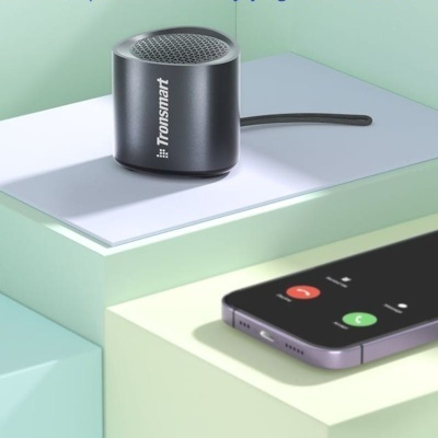 Coluna portátil preta Tronsmart com cabo junto a smartphone