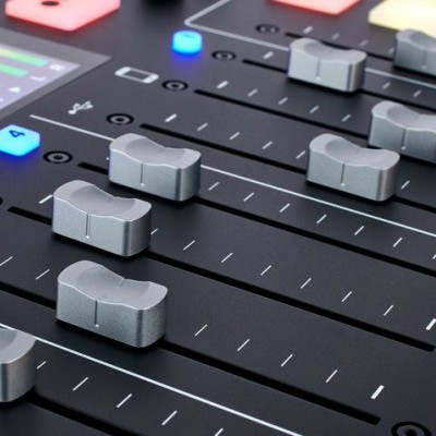 Mesa de mistura de áudio com botões iluminados e controlos deslizantes cinzentos