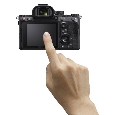 Câmara digital Sony preta com uma mão tocando o ecrã LCD