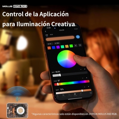 Smartphone com app de controlo de iluminação RGB numa mão, mostrando seletor de cor e sliders, com fundo desfocado