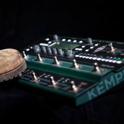 Pedal de efeitos para guitarra KEMPER com bota castanha pressionando pedal