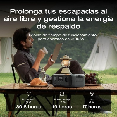 Homem em campismo com lanterna, lanche e dispositivo eletrónico numa mesa de madeira