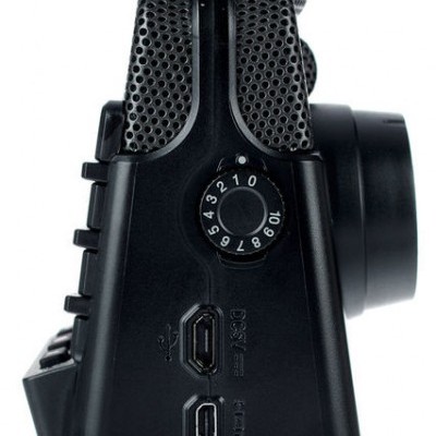 Câmara digital preta vista de lado com botão circular e portas USB e HDMI