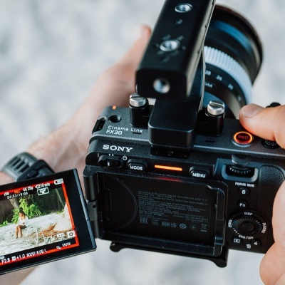 Câmara Sony preta com visor articulado colorido e lente grande a ser segurada