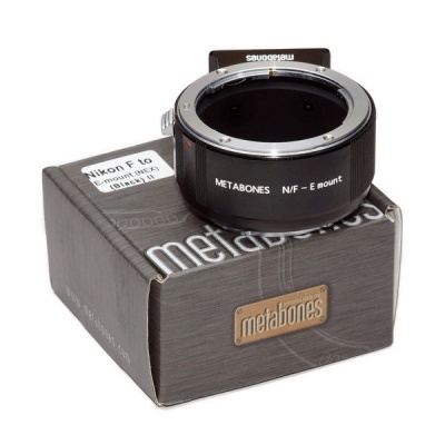 Adaptador Metabones preto sobre caixa preta com texto e etiqueta Nikon F to E mount