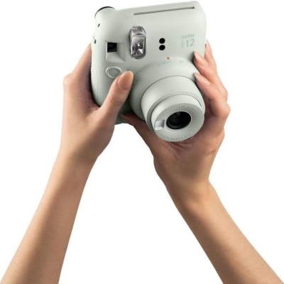 Câmara instantânea Fujifilm Instax 112 cinza claro segurada por duas mãos.