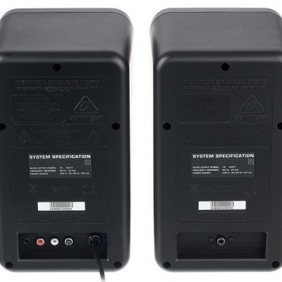 dois altifalantes pretos vistos de trás com etiquetas e conectores de áudio