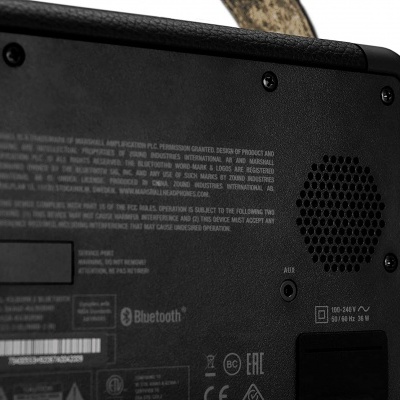 Painel traseiro preto de dispositivo com texto, grelha de som, entrada AUX e logotipos técnicos