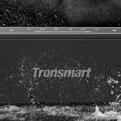 Coluna portátil Tronsmart preta com gotas de água num fundo escuro